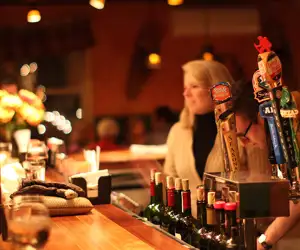 Bartender standing at the bar next to the beer taps